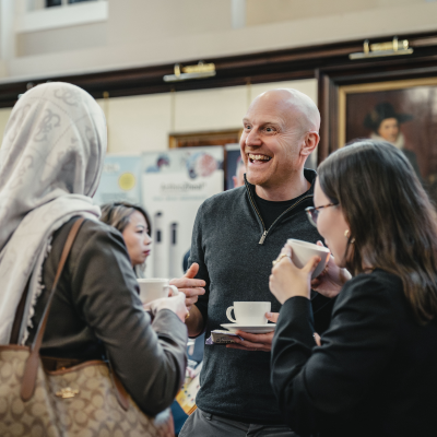 Three people laughing and smiling enjoying a coffee
