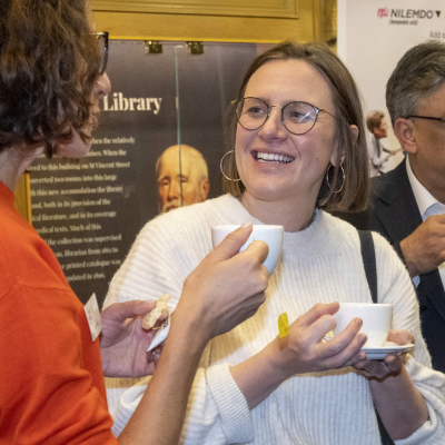 two people smiling whilst drinking coffee