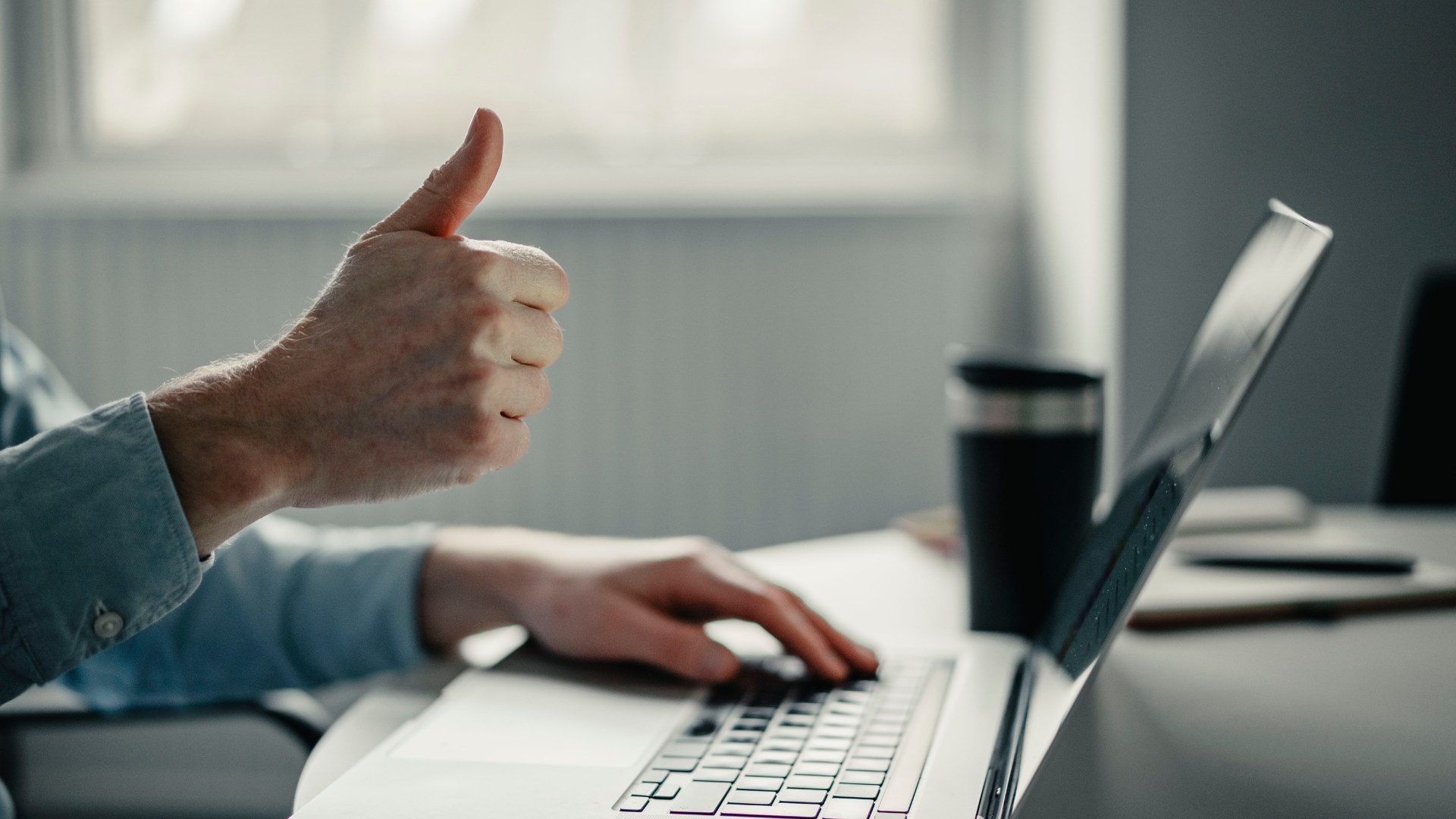 Someone giving a thumbs up at a laptop