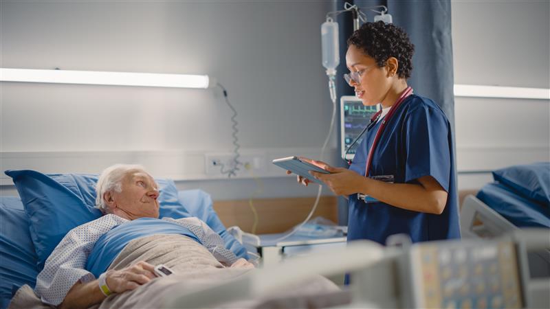 doctor with clipboard talking to patient in hospital bed