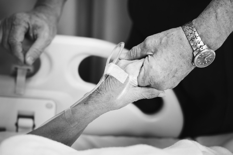 dr holding a patients hand with IV in