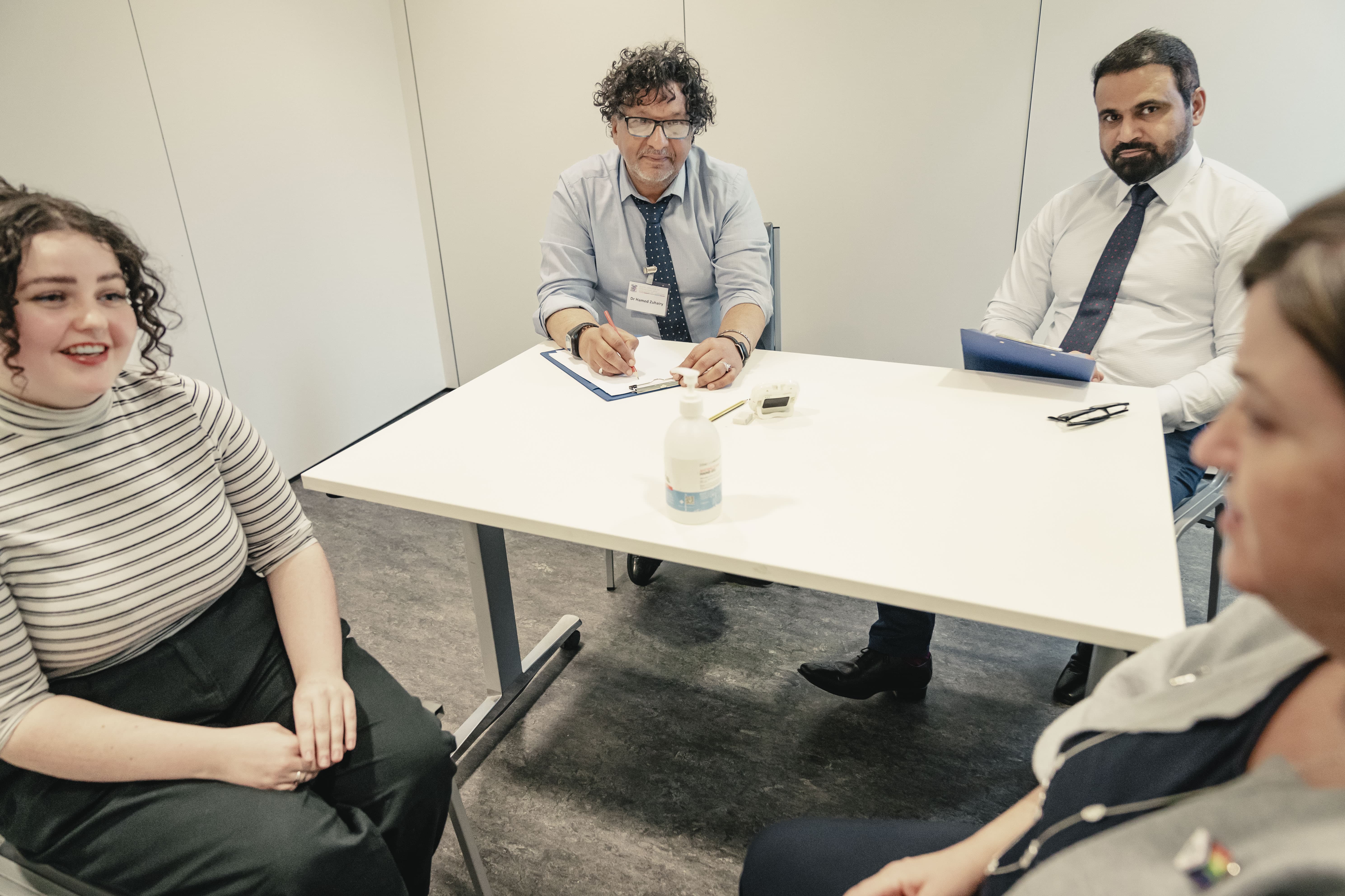 A group of examiners and a candidate engaged in a clinical scenario discussion during the MRCP(UK) PACES exam, seated around a table in a professional setting.