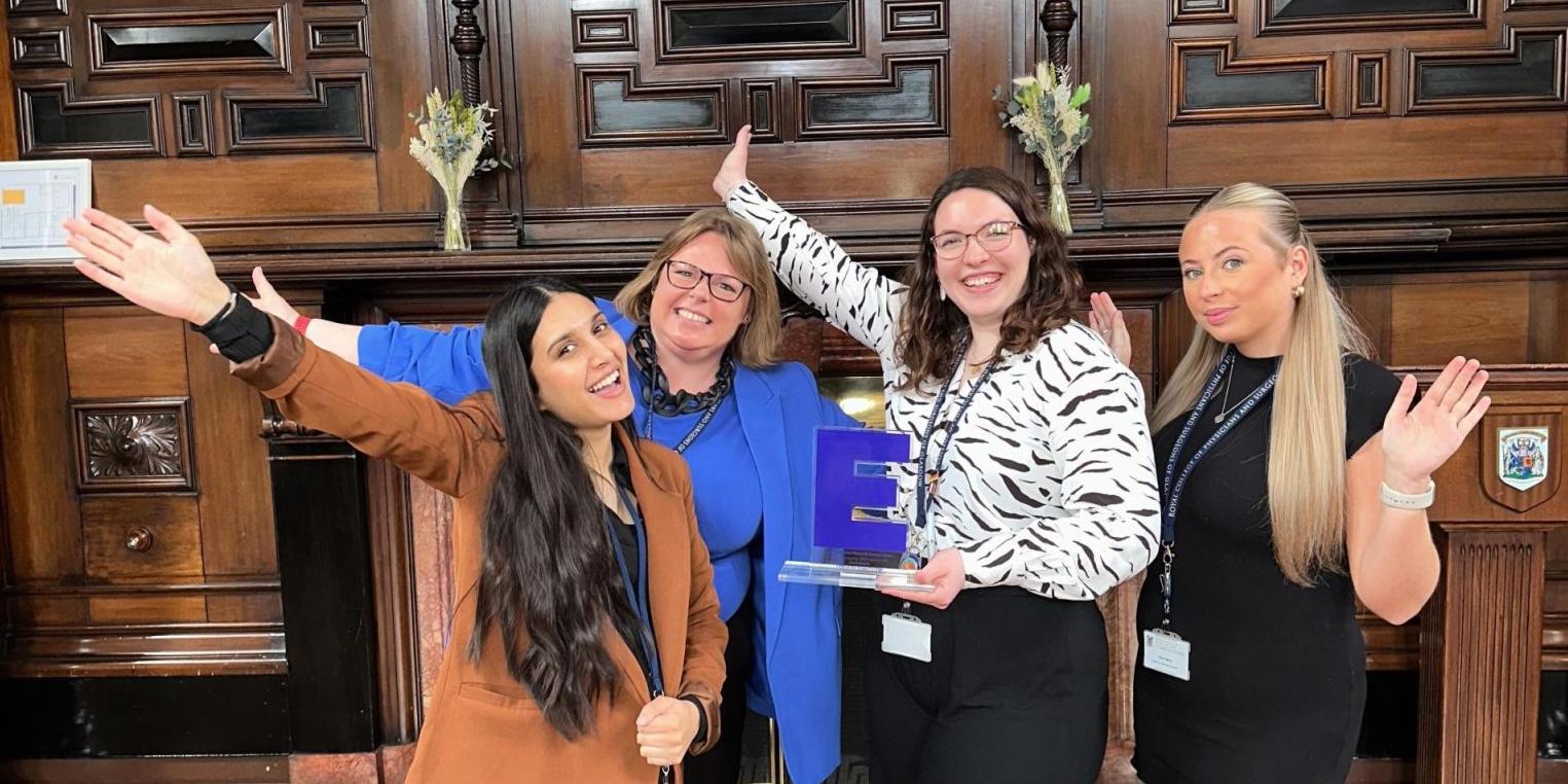 four women standing celebrating an award